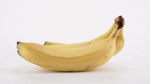 Three Fresh Yellow Bananas Rotating on White Background
