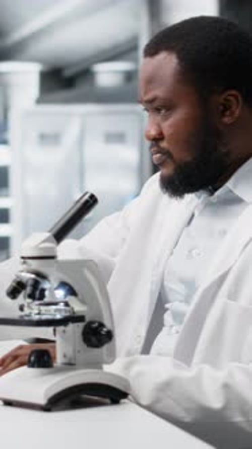 Scientist Adjusting Microscope in Bright Laboratory Setting