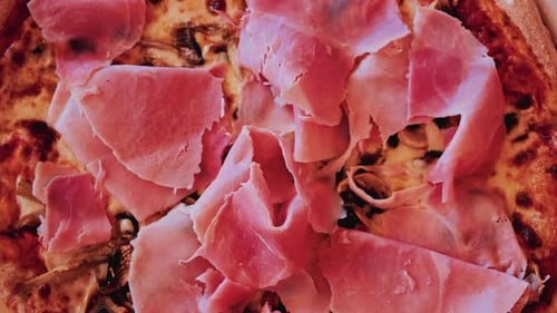 Overhead shot of a freshly baked pizza generously topped with thin slices of prosciutto