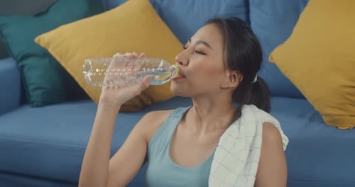 Woman Drinking Water After Home Workout Indoors