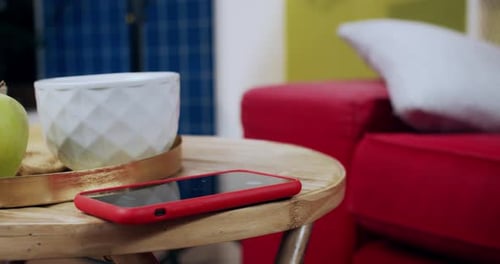 Phone with red case on table gets picked up