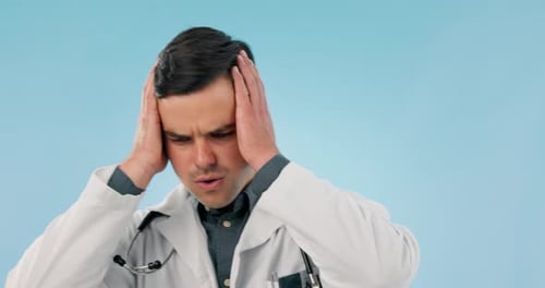 Burnout, man and doctor with stress, headache and healthcare on a blue studio background