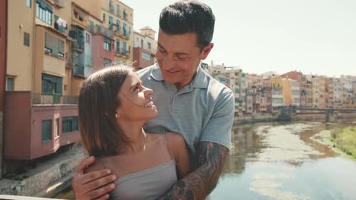 Smiling Girl and Man Embracing on City Bridge