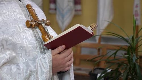 16. A priest with a cross reads a book during a service.