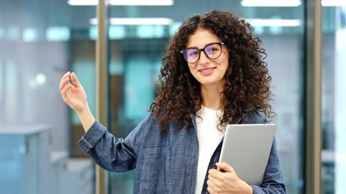 Smiling Businesswoman Gestures in Modern Office with Tablet