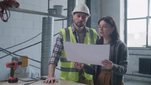 Engineer and Client Discussing Architectural Plan at Construction Site