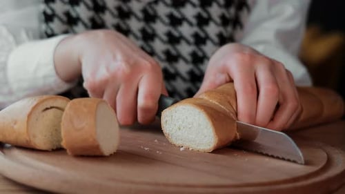 Woman Slicing Fresh Bread on a Wooden Board Closeup of a Woman Cutting a Loaf of Fresh Bread Into