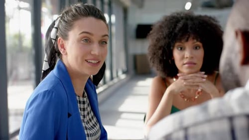 Three diverse colleagues discussing while sitting on a table together at office