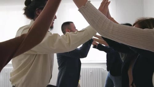 team of diverse professionals celebrates a successful project with a high-five in a modern office