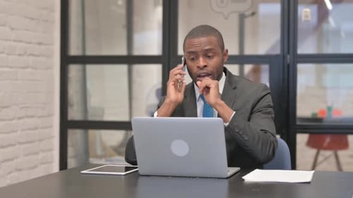 African Businessman Talking on Phone in Office