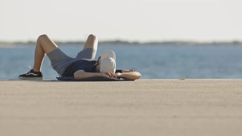 Ein Mann in Sportkleidung ruht ruhig am Strand und liegt auf seinem Rücken