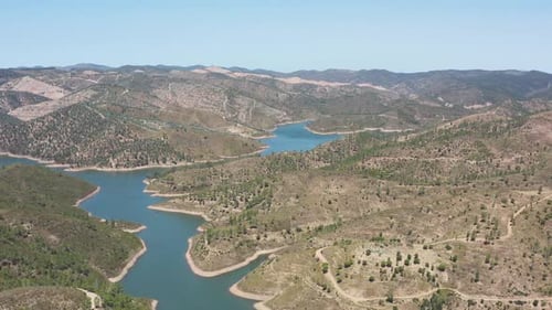 Drone flight over a reservoir that occupies an entire valley between the mountains.