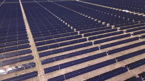 Ein großer Solarpark mit Reihen von Sonnenkollektoren bei hellem Tageslicht, Luftbild