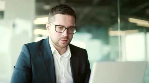 Close up. Confident businessman talking on a video call sitting at a workplace in office.