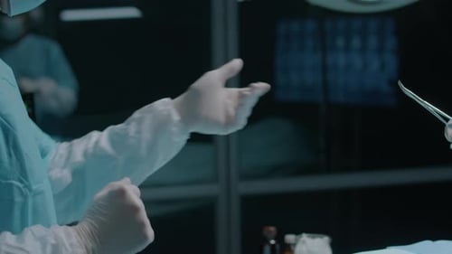 Surgeon Giving Forceps to Intern during Medical Operation