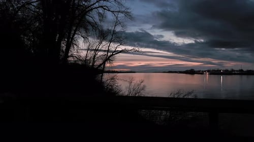 Side pan of beautiful pink sunset sky after sun has dipped over the horizon view overlooking railing