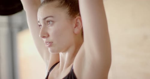 Focused unaltered caucasian woman free weight training at gym lifting barbell, in slow motion