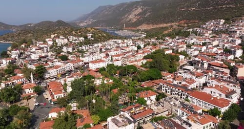 Aerial establishing dolly of Kas town in Antalya, Turkey, with red-tiled rooftops and lush green hil