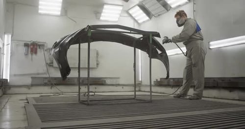 Craftswoman Painting Car Bumper in Workshop