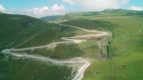 Aerial Over Winding Asphalt Road Among Mountains Covered with Green Grass in Highlands of Caucasus