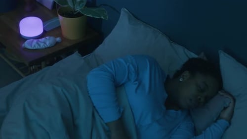 Black Woman Sleeping in Bed in Dark Room at Night