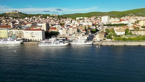 Parallel drone flight, next to a small croatian city. In the foreground is water and a yacht.