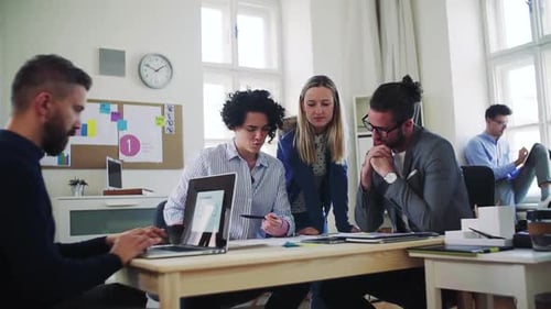 Young business team collaborating on a laptop in a modern open office space