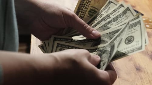 Counting Cash: Hands Count One Hundred Dollar Bills