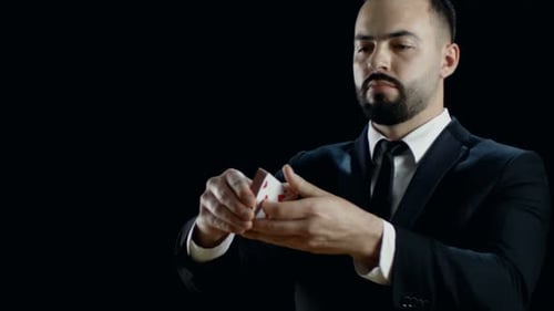 Close-up of a Professional Magician in a Black Suit Performing Card Trick. Throwing and Catching Ca