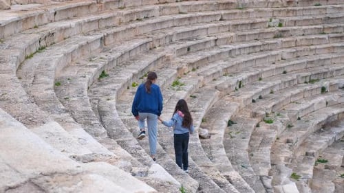 Tourists Walking Down Ancient Amphitheater Stone Steps