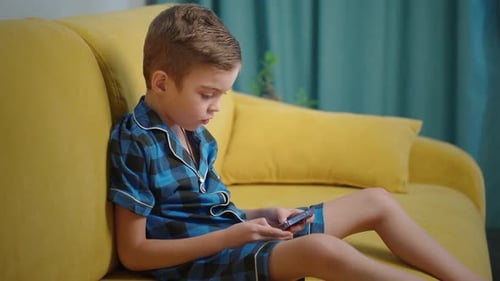 Boy on Couch Looking at Mobile Phone