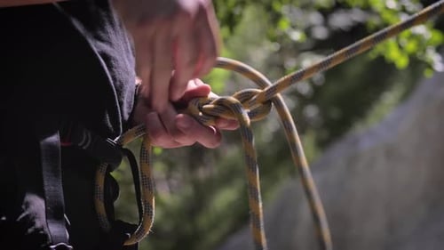 Climber makes a knot with the rope