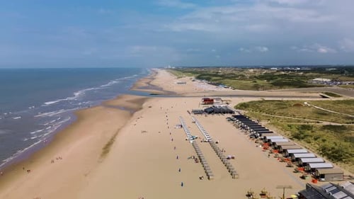 A beautiful aerial view of a sandy beach with rows of beach huts, people relaxing by the shore