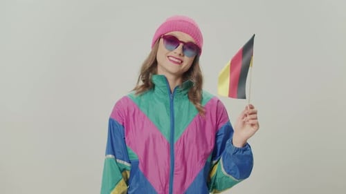 Mädchen im 80'90er-Stil winkt vor der deutschen Flagge