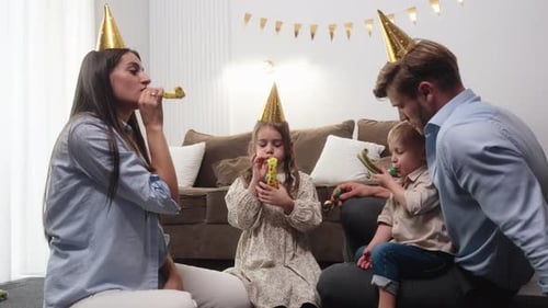 Family Celebrating Birthday Together with Party Blowers