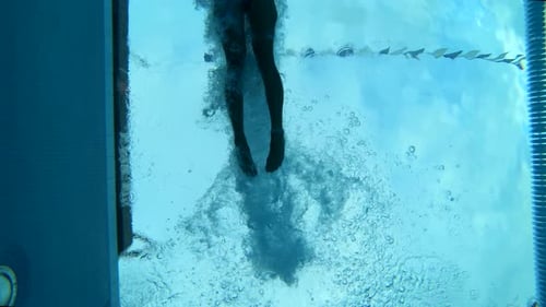 Underwater shot of a woman diving into a lap pool wearing professional swimwear.