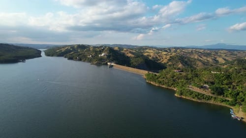 Establishing shot of artificial lake and green mountain landscape of Dominican Republic. Dam stoppin
