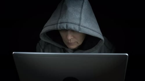 Hooded Person Uses Laptop in the Dark
