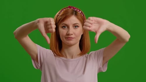 Woman, thumbs down and face by green screen for disagree, review and bad news by background.