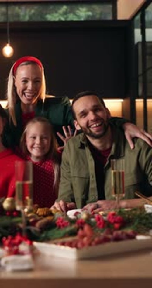 Family Poses for Holiday Photo Around Dinner Table