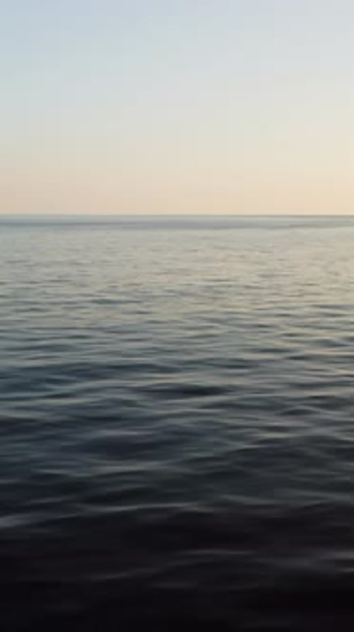 La caméra de vision aérienne verticale de la surface de l'eau de mer au coucher du soleil survole les reflets calmes du soleil de la mer dorée