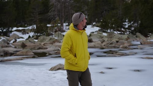 Hiker Walking in Snowy Mountain Forest Trail with Backpack and Trekking Poles