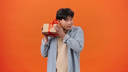 Man Examines Gift and Shakes Box Trying to Guess Content