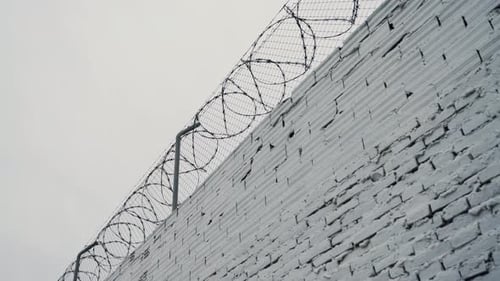 Security systems restricted area. Sharp razor blades on barbed wire. Prison wall.