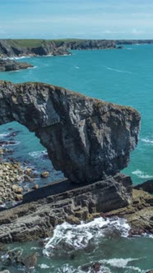 Natürlicher Felsbogen an der Küste von Pembrokeshire, Wales, in Vertikal