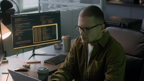 Concentrated Young Male Programmer Working Overnight in Computer Office