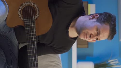 Man Playing Acoustic Guitar Sitting Down Inside