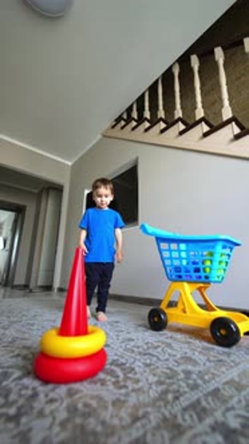 El
precioso bebé coge los detalles del juguete del carrito. Un niño lindo construye una pirámide en el suelo.