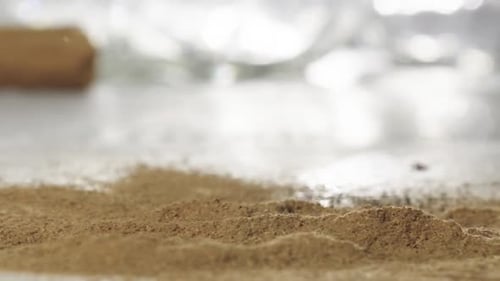 Slow motion shot of Cinnamon sticks fall over Brown powder in Table, Close up