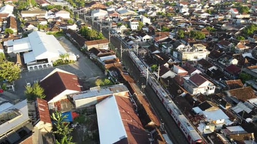 Aerial view of passenger train crossing rail bridge in near Tugu Station.